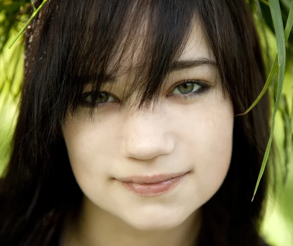 Portret van brunette tiener meisje op groen buiten. — Stockfoto