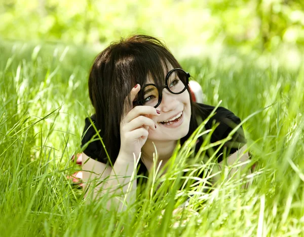 Młoda dziewczyna w okularach na zielonej trawie. — Zdjęcie stockowe