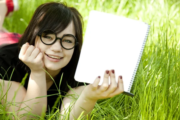 Mladá dospívající dívka s notebookem na zelené trávě. — Stock fotografie