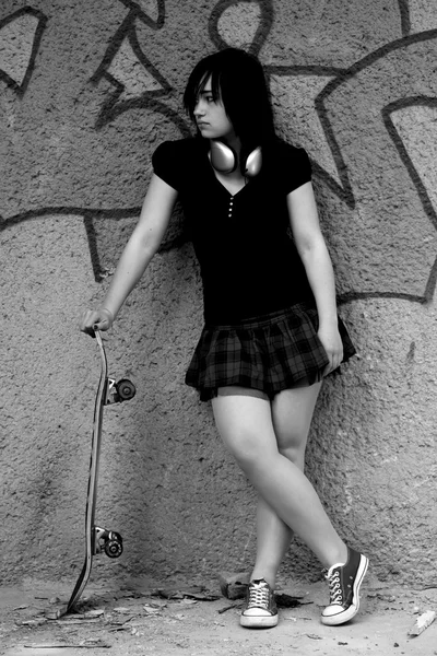 Κορίτσι εφήβων brunette με skate. φωτογραφία σε μαύρο και άσπρο στυλ. — Φωτογραφία Αρχείου
