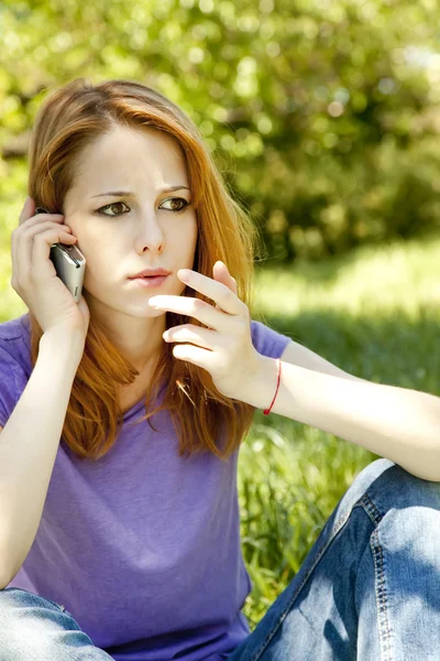 Menina ruiva surpresa com telefone celular no parque no verão t — Fotografia de Stock
