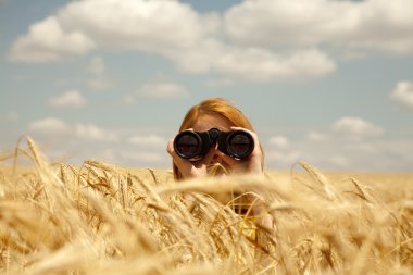 Redhead girl with binocular at wheat field. clipart