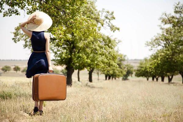 Eenzaam meisje met koffer op platteland. — Stockfoto
