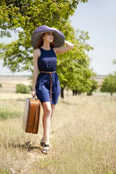 Eenzaam meisje met koffer op platteland. — Stockfoto