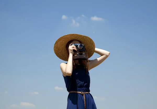 Roodharige meisje met retro camera bij blauwe hemel achtergrond. — Stockfoto
