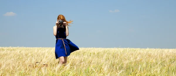 Rödhårig tjej på vårfältet med retrokamera. — Stockfoto