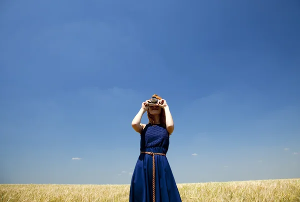 Rödhårig tjej på vårfältet med retrokamera. — Stockfoto