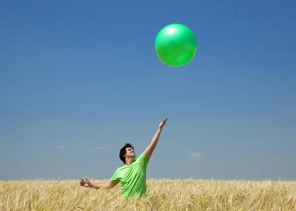 麦畑で緑色のボールを持つ男性κοκκινομάλλα κοπέλα στο πεδίο άνοιξη με ομπρέλα. — ストック写真