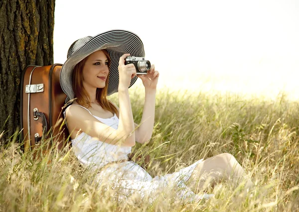 빈티지 카메라와 함께 나무 근처에 앉아 빨간 머리 소녀. — 스톡 사진