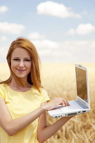Rödhårig tjej med laptop på vete fält. — Stockfoto