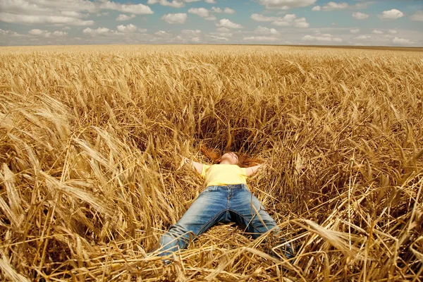 Рыжая девушка спит на пшеничном поле летом . — стоковое фото