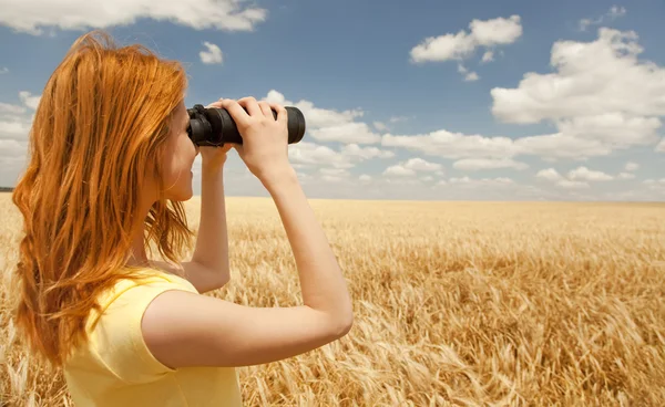 Menina ruiva com binocular no campo de trigo . — Fotografia de Stock