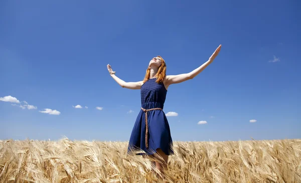 Rusovláska dívka v pšeničné pole v letní den. — Stock fotografie