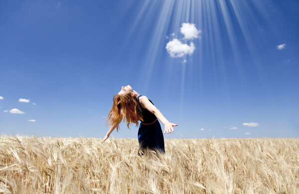 Redhead girl at wheat field in summer day.