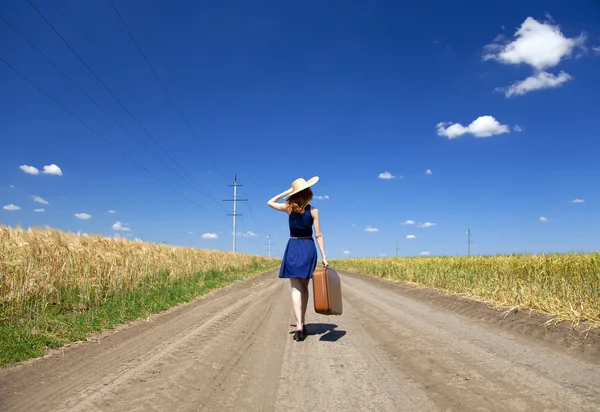 Menina solitária com mala na estrada de campo . — Fotografia de Stock