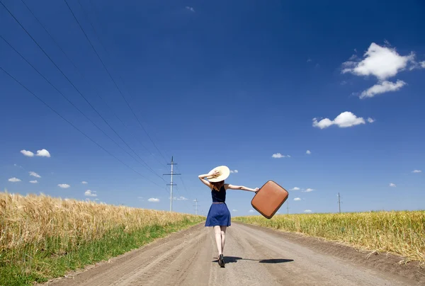 Самотня дівчина з валізою на заміській дорозі . — стокове фото