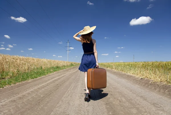 Eenzaam meisje met koffer in landweg. — Stockfoto
