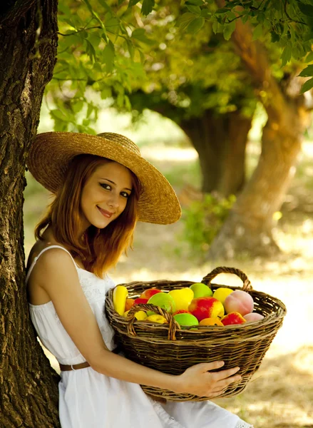 Menina ruiva bonita com frutas na cesta no jardim . — Fotografia de Stock