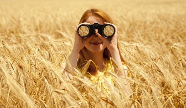 Redhead girl with binocular at wheat field. clipart