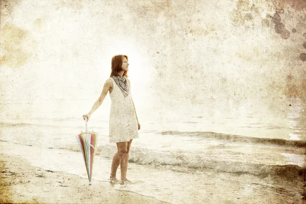 Dívka s deštníkem na pobřeží moře. Foto ve starém stylu obrázku. — Stock fotografie