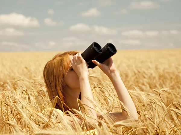 Rotschopf Mädchen mit Fernglas am Weizenfeld. — Stockfoto