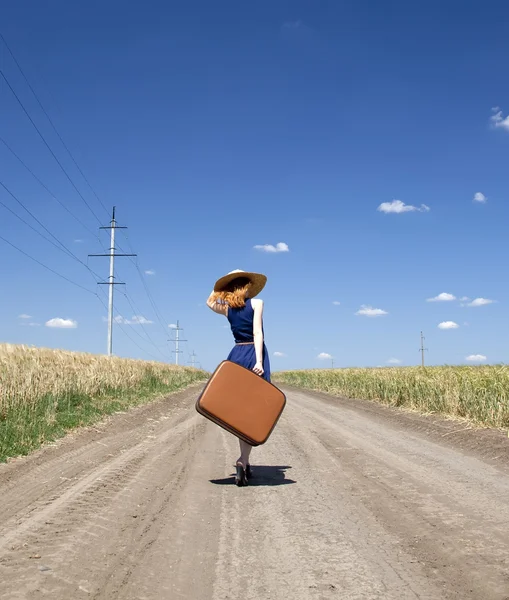 Einsames Mädchen mit Koffer an Landstraße. — Stockfoto