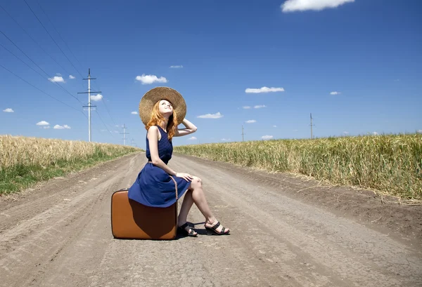 Osamělá dívka s kufrem na venkovské silnici. — Stock fotografie