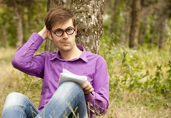 Lustige Männer mit Brille machen Hausaufgaben im Park. — Stockfoto
