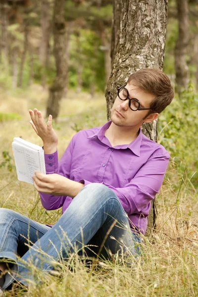 幽默的男人戴着眼镜做家庭作业在公园. — 图库照片
