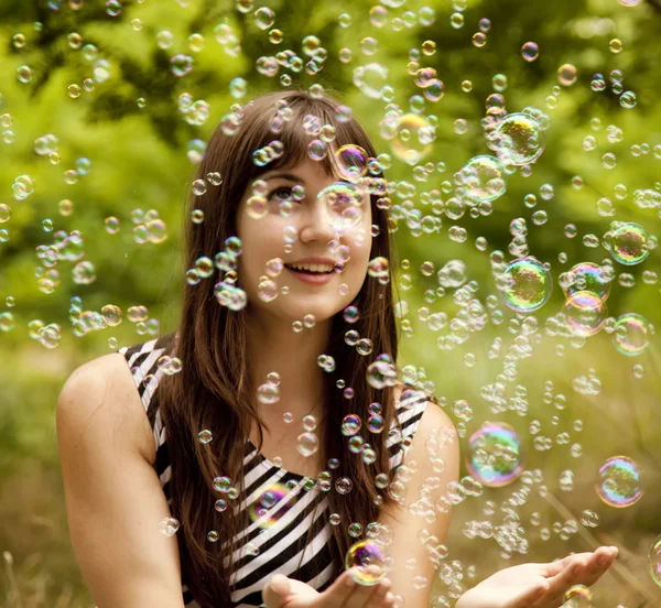 Morena chica en el parque bajo la lluvia de jabón burbuja . — Foto de Stock