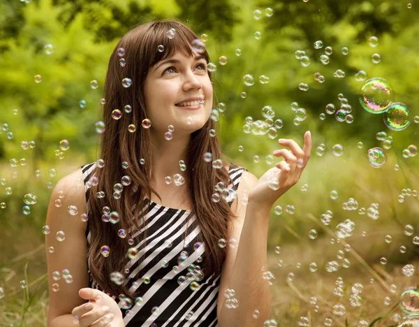 Brunett flicka i parken under såpbubbla regn. — Stockfoto
