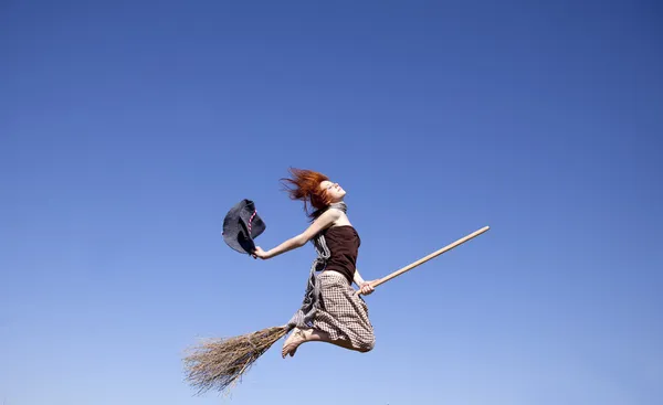 Kızıl saçlı genç cadı uzak uçan süpürge üzerinde — Stok fotoğraf