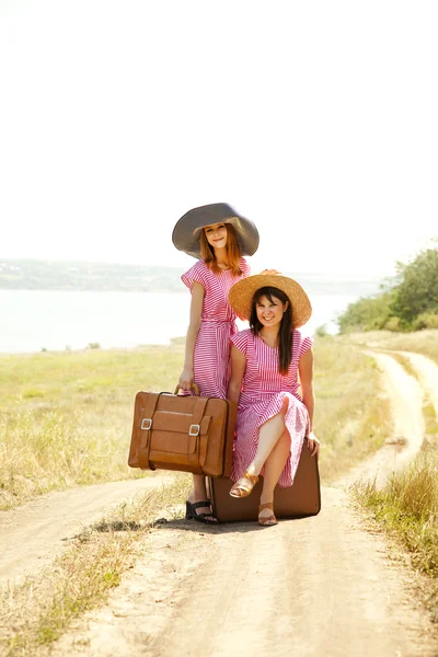 Duas meninas estilo retro com malas no campo . — Fotografia de Stock
