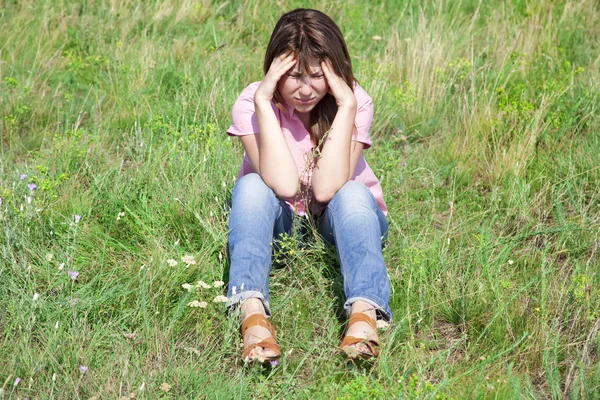 Triest meisje op groen gras op platteland. — Stockfoto