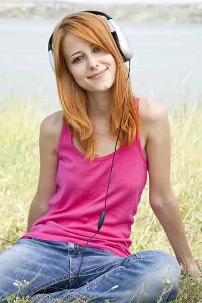 公園でヘッドフォンで赤毛の女の子. — ストック写真