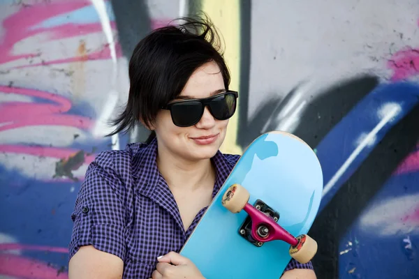 Chica de estilo con monopatín cerca de la pared de graffiti . — Foto de Stock