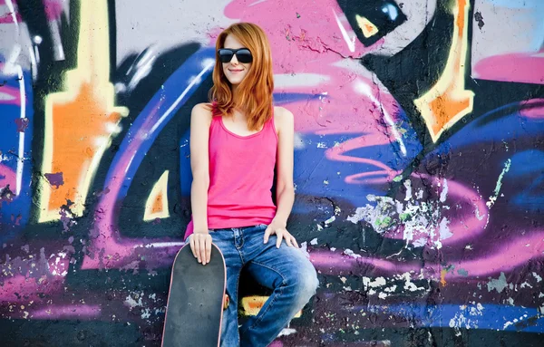Stile ragazza con skateboard vicino muro graffiti . — Foto Stock