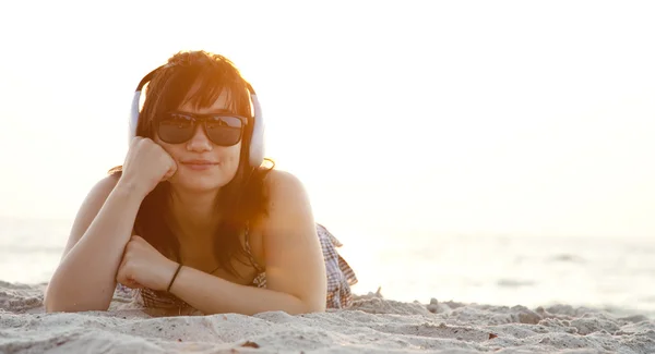 Piękna brunetka dziewczyna ze słuchawkami w piasku na plaży. — Zdjęcie stockowe