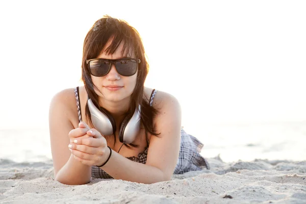 Vacker brunett tjej med hörlurar på stranden sand. — Stockfoto