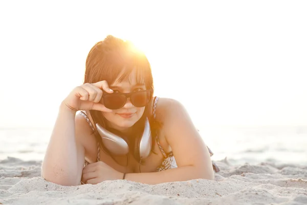Hermosa chica morena con auriculares en la playa de arena . —  Fotos de Stock