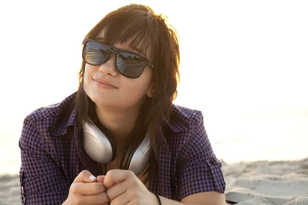 Schöne brünette Mädchen mit Kopfhörern am Strand Sand. — Stockfoto