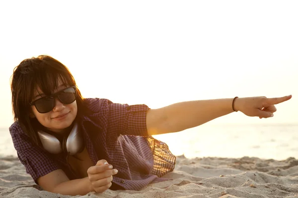 Menina morena bonita com fones de ouvido na areia da praia . — Fotografia de Stock