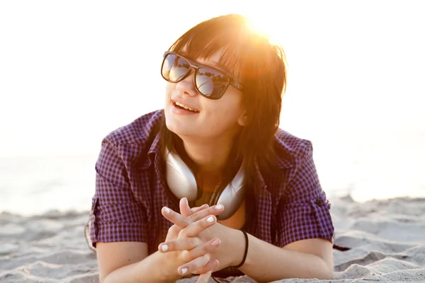 Belle fille brune avec écouteurs à la plage de sable . — Photo
