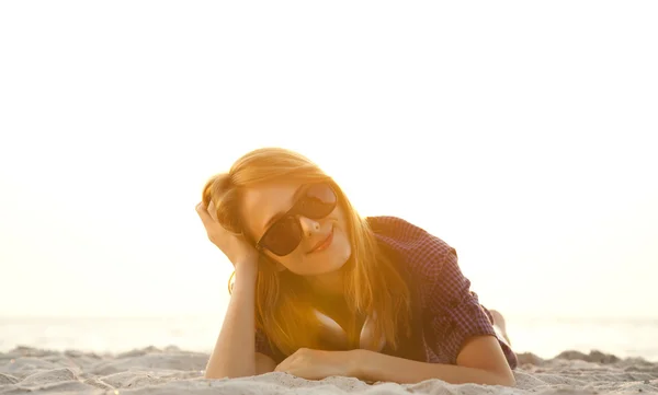 Menina ruiva bonita com fones de ouvido na areia da praia . — Fotografia de Stock