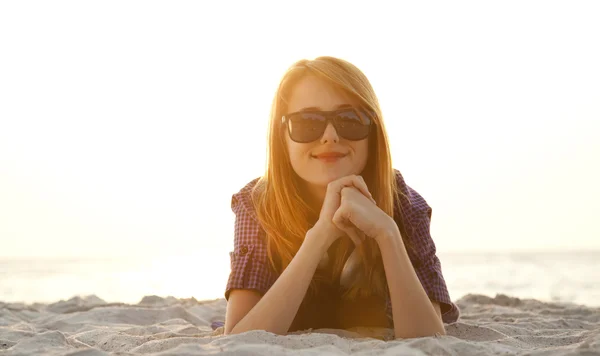 Mooi roodharig meisje met koptelefoon op strand zand. — Stockfoto
