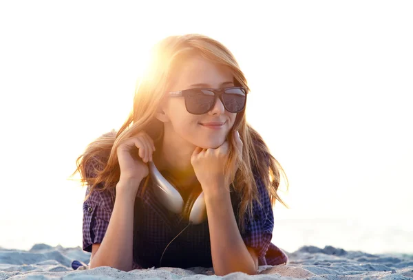 Mooi roodharig meisje met koptelefoon op strand zand. — Stockfoto