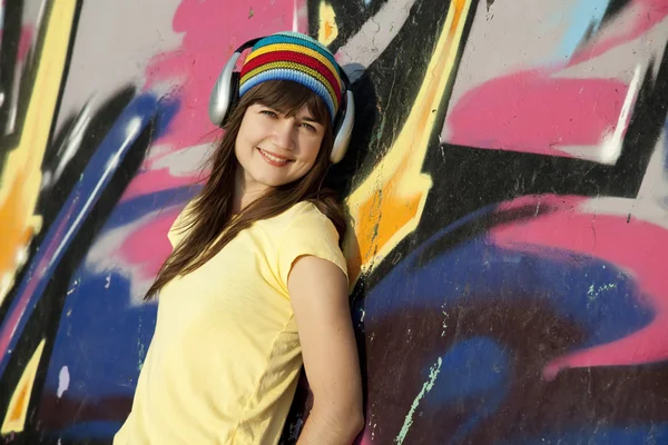 Bella ragazza bruna con cuffie e graffiti parete a bac — Foto Stock
