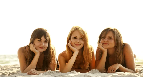 Três belas jovens namoradas em biquíni na praia no sunr — Fotografia de Stock
