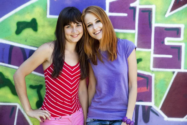Twee vriendinnen in de buurt van graffiti muur. — Stockfoto