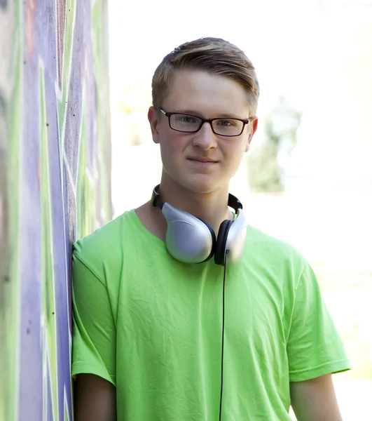 Tiener jongen met koptelefoon in de buurt van graffiti muur. — Stockfoto